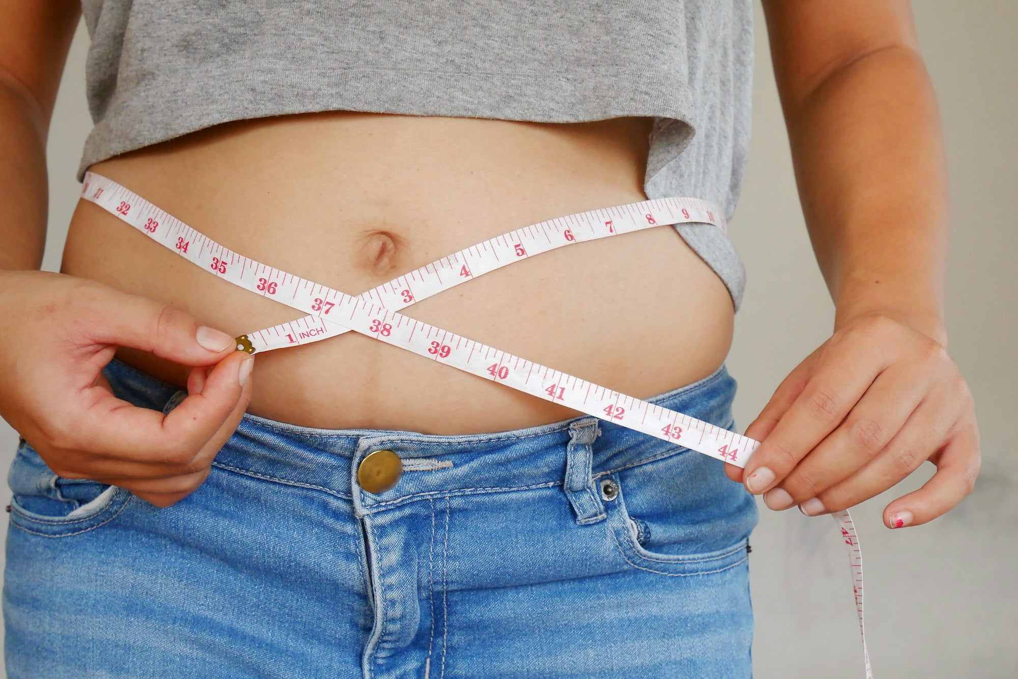 Healthy care. Woman measures her waist with overweight belly and abdomen.